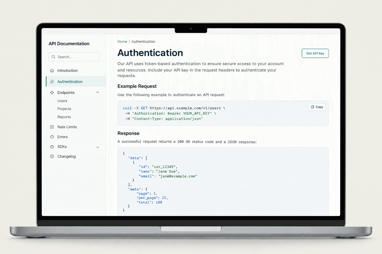 A laptop showing light-themed API documentation with a code example.