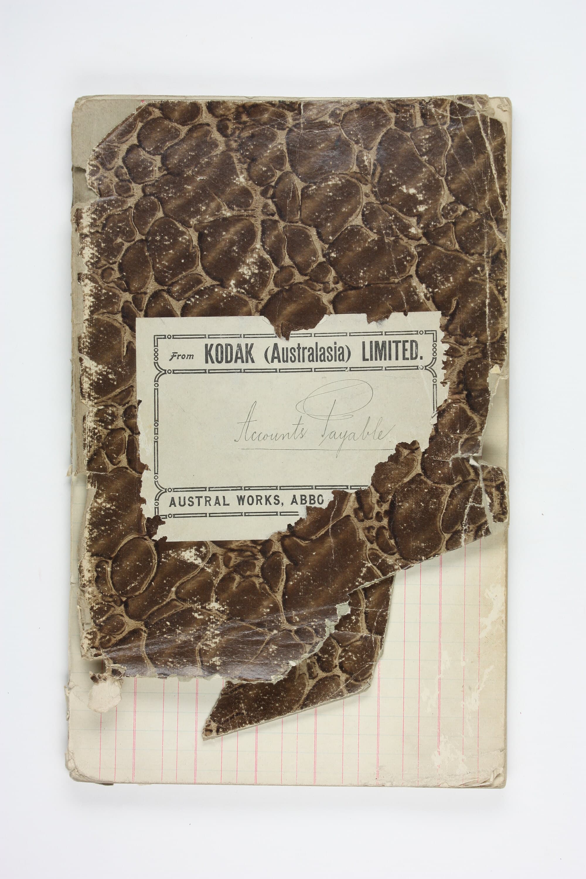 A 1920s accounts payable ledger, its marbled cover worn through to the ruled pages.